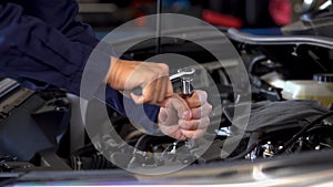 Hand using wrench to repair engine, car service