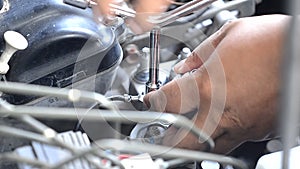 Hand using a wrench to tighten the nut engine grounded of car