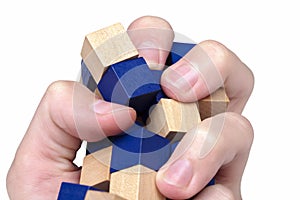 Hand violently squeezing, crushing and knocking down a structure made of wooden blocks