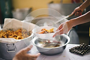 The hand of the wanderer extends to receive food from donations. With volunteers scooping food: the idea of helping with hunger