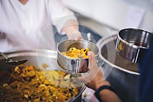 The hand of the wanderer extends to receive food from donations. With volunteers scooping food: the idea of helping with hunger