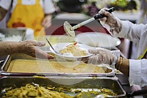 The hand of the wanderer extends to receive food from donations. With volunteers scooping food: the idea of helping with hunger