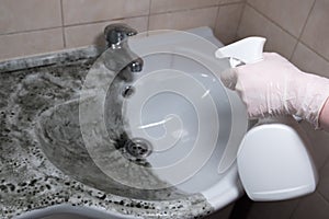 Hand wash basin. Half the sink is clean, the other half is dirty. The hand in a protective glove holds the cleaning and