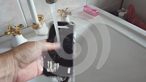 Hand wash mobile phone under tap water against covid 19 , coronavirus and bacteria