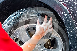 Hand washing car tire with black sponge