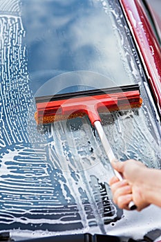 Hand washing car window with mop