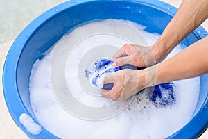 Hand washing clothes in Blue basin