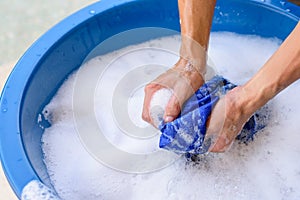 Hand washing clothes in Blue basin