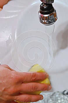 Hand washing dishes. Hand with sponge and sink in kitchen washing dirty dishes - plate