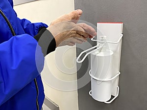 Hand washing with disinfectant close-up. Elderly woman disinfects her hands with an antiseptic gel automatic dispenser