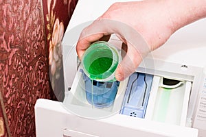 Hand with washing gel close up. The man pours the washing gel into the compartment of the washing machine