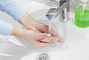 hand washing with soap or gel under running water in the washbasin, cleanliness and hygiene, woman& x27;s hands dressed