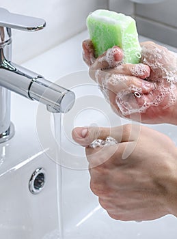 Hand washing with soap. Preventive measures against infection. A young guy washes his hands with soap in the bathroom. Body