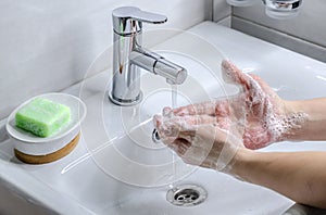 Hand washing with soap. Preventive measures against infection. A young guy washes his hands with soap in the bathroom. Body