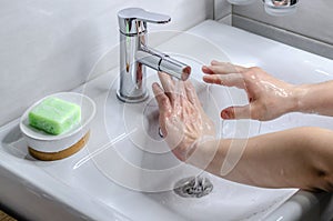 Hand washing with soap. Preventive measures against infection. A young guy washes his hands with soap in the bathroom. Body