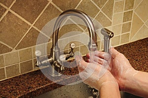 Hand washing under water flowing out a faucet