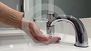 Hand washing. Woman washes soap suds from her hands under running water. Washing hands in the bathroom.