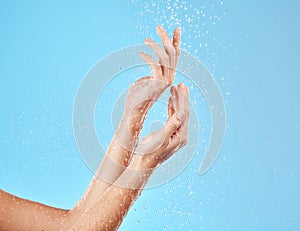 Hand, water and cleansing for health, wellness and bodycare on a blue studio background. Hands, fingers and shower