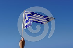 Hand waving Greek flag in the air for a national celebration. photo