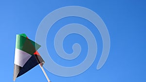 Hand waving national flag of Palestine against clear blue sky close-up slow motion.