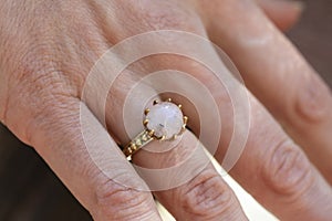 hand wearing brass ring with shiny moonstone gemstone