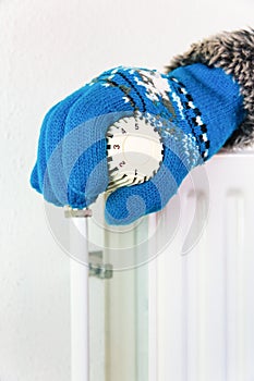 Hand wearing glove turns heating valve in winter