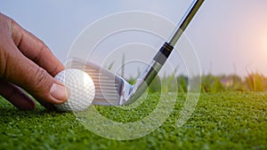 Hand-wearing golf glove holding a white golf ball on green background