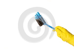 A hand wearing a yellow cleaning glove holding a cleaning brush on a white background