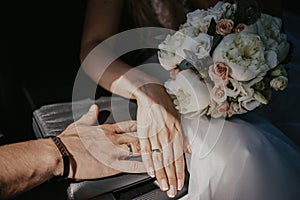 A hand of wedding couple touch each other. Hands newlyweds with wedding rings close up. Bridal hands with rings on black leather
