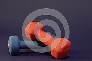 Hand weights, red and blue, each of Five pounds, close-up and isolated on dark blue background