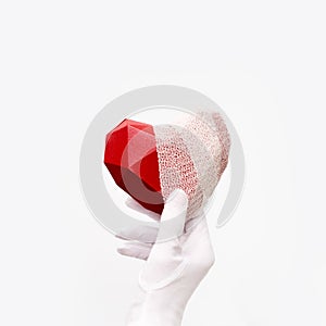 Hand with white fabric glove holding red bandaged heart on white background. Healht care, love concept