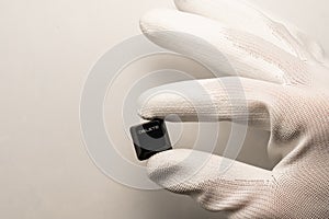 A hand in a white glove holds a black keyboard button with a white DELETE inscription on a white background