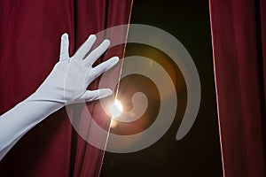 Hand in a white glove pulling curtain away