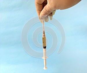 Hand with white latex glove holding syringe ready to use