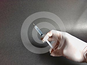 Hand with white latex glove with injection with black background