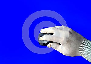 Hand with white latex glove using a computer mouse in a laboratory on a blue background. medical concept