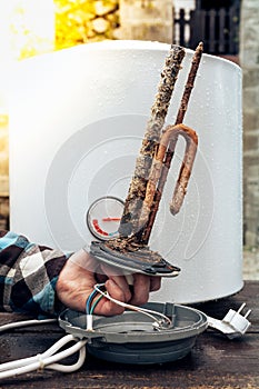 The hand of a white man, demonstrates the destructive effect of scale on the element of the boiler