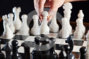 Hand with white pawn over chessboard