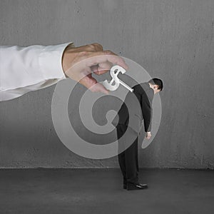 Hand windering winder on businessman's back, concrete background