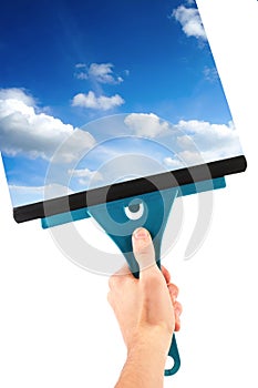 Hand with window cleaning tool and blue sky