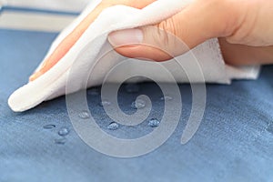 hand wipes drops of water from a cloth. Water drops on waterproof textile material. short depth of field. Waterproof
