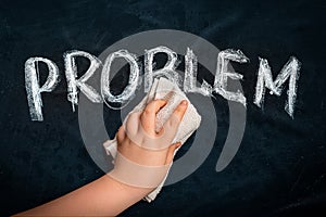 Hand wiping off chalk word PROBLEM on black chalkboard using rag. Remove problem issue solution concept