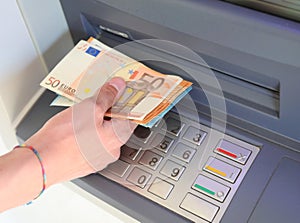 Hand withdrawing money from the ATM with European banknotes