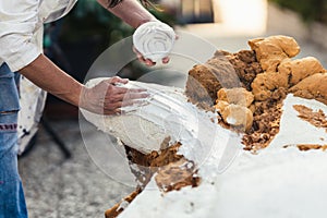 Hand of a woman applying paste on the surface of a polystyrene figure photo