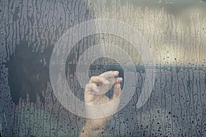Hand of woman in the car window with rain drop. Loneliness and depression concept.