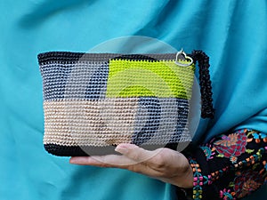 The hand of a woman carrying a knit bag