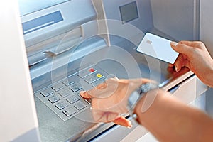 Hand of a woman with a credit card, using an ATM. Woman using an ATM machine with her credit card. photo