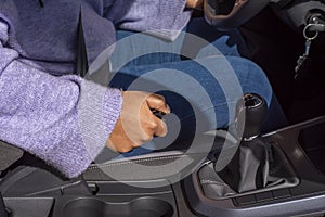 Hand woman driver pulling the hand brake in car