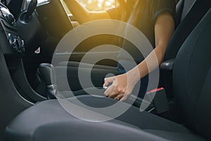 Hand woman driver pulling the hand brake inside modern car