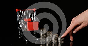Hand of Woman and Euro Coins in Trolley against Black Background